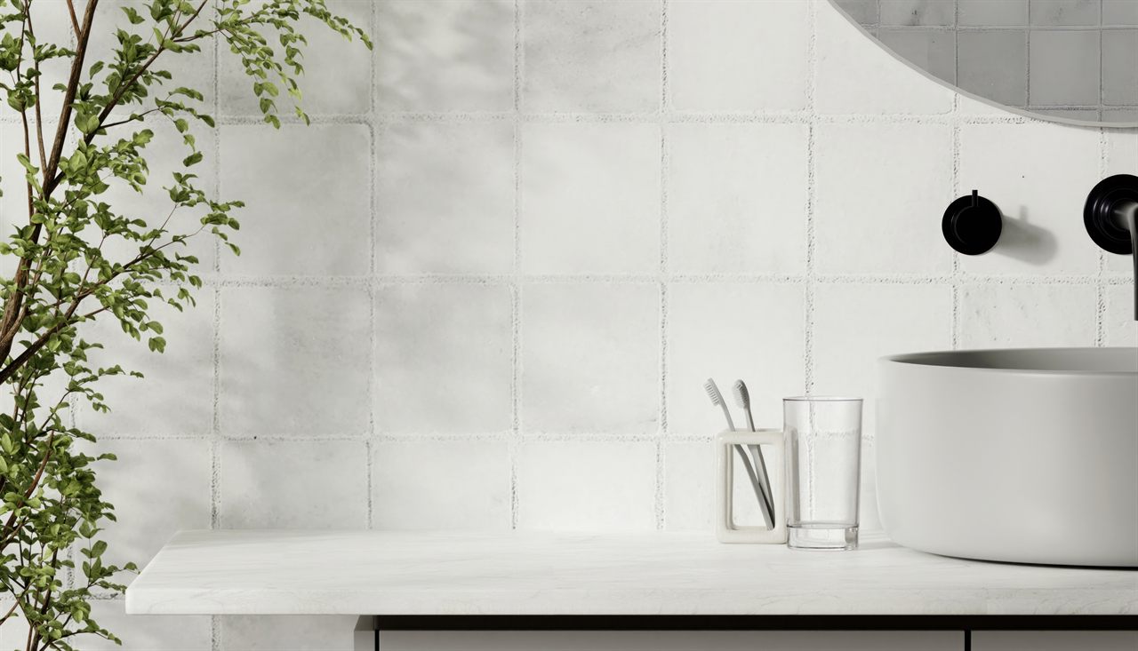 Badkamer met witte wandtegels in handgemaakte look, een waskom op een wit werkblad en een zwarte inbouwkraan